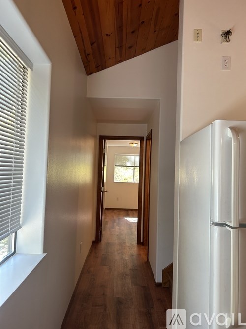 A long hallway with a white fridge on the right.