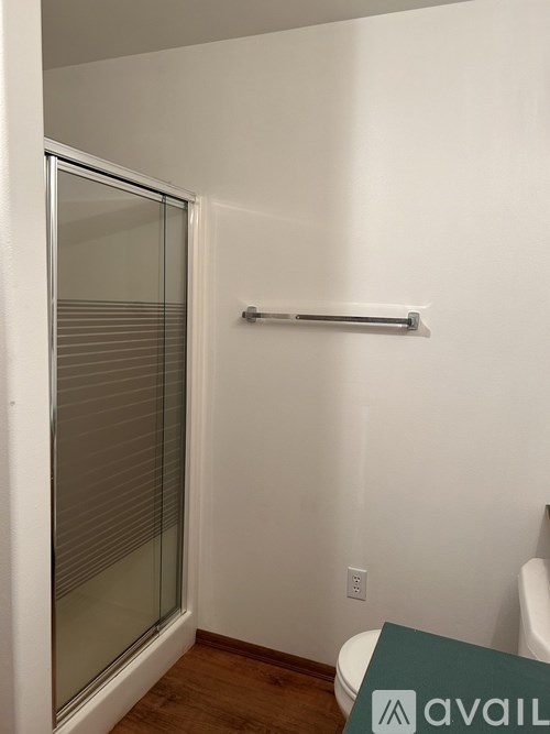 A bathroom with a toilet, a glass door and a towel bar.