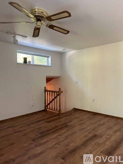 A room with a ceiling fan and wooden flooring.