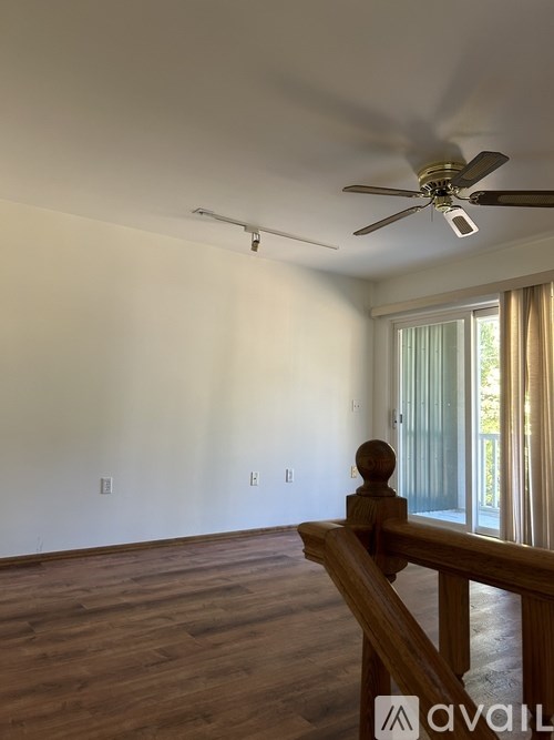 A room with a ceiling fan and wooden flooring.