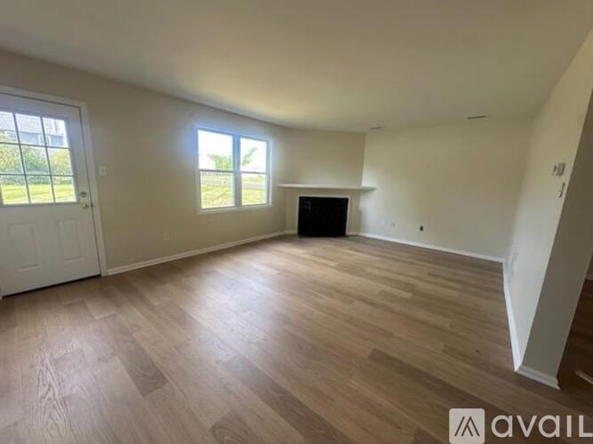 A spacious room with wooden flooring and a large window.
