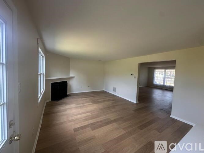A spacious room with wooden flooring and a black piece of furniture.