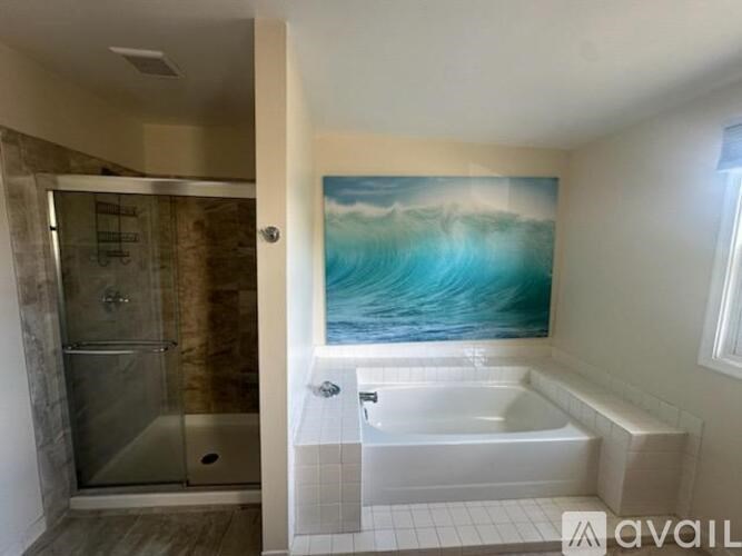 A bathroom with a large painting of a wave above a bathtub.