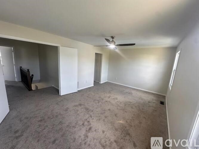 A spacious room with a ceiling fan and carpeted floor.