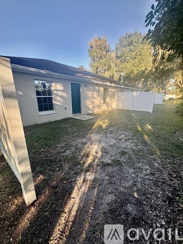 A small house with a green door and a white fence in the yard.