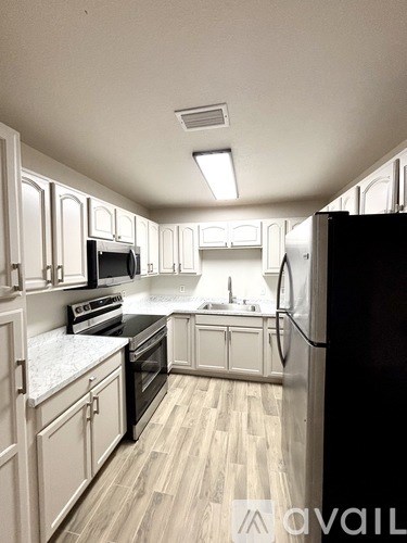 A kitchen with white cabinets and a black refrigerator.