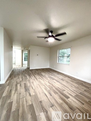 A room with a ceiling fan and wooden flooring.