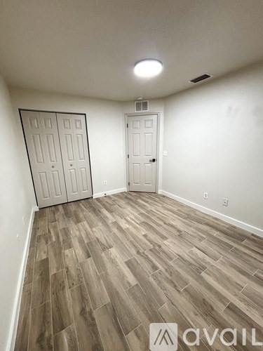 A room with wooden flooring and two doors.