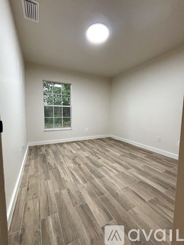 A room with wooden flooring and a window.