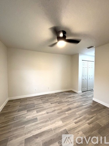 A room with a ceiling fan and a wooden floor.