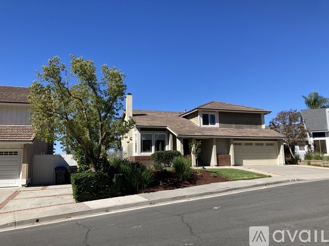 A house with a tree in front and a garage door opener on the wall.