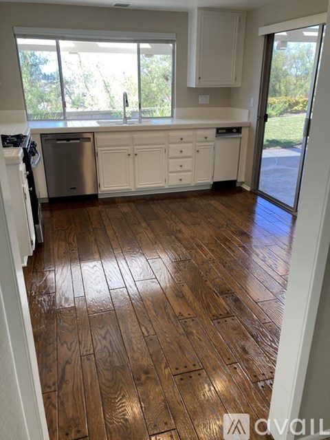 A kitchen with white cabinets and a wooden floor.