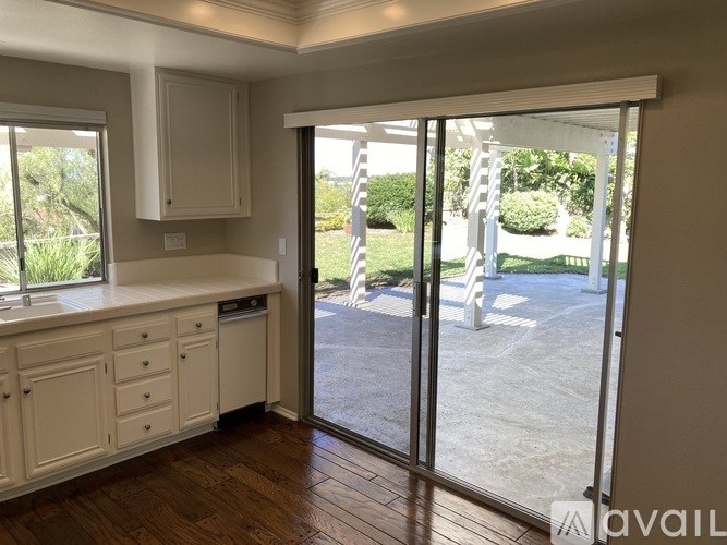 A kitchen with white cabinets and a wooden floor.