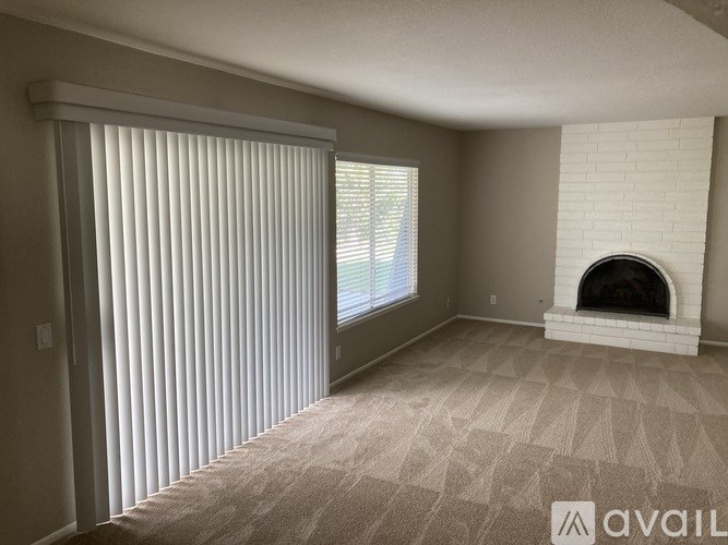 A room with a fireplace and a window with blinds.