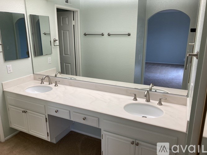 A bathroom with a double sink vanity and a mirror above it.