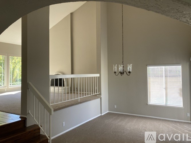 A living room with a staircase and a chandelier.