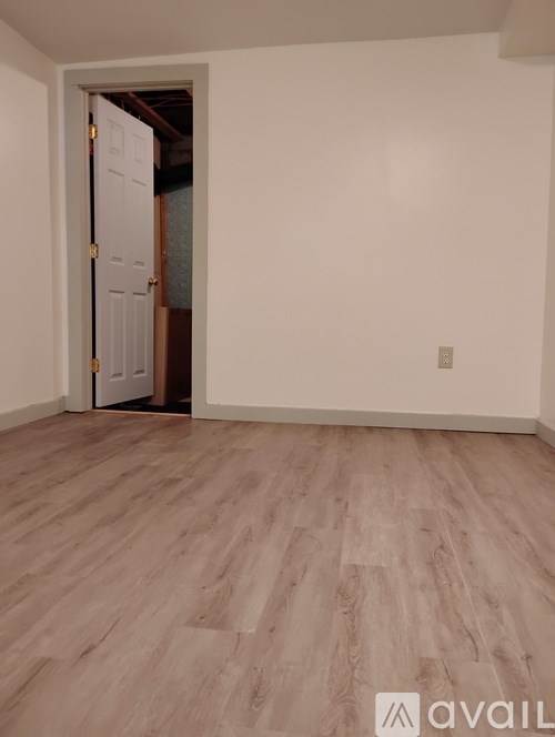 A room with a white door and wooden flooring.
