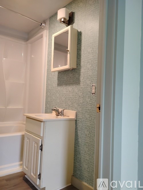 A white bathroom cabinet with a mirror above it.