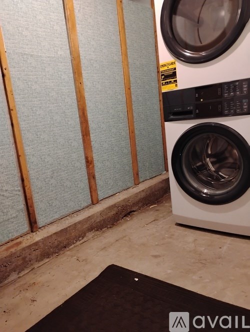 A washing machine is in front of a wall with a blue panel.
