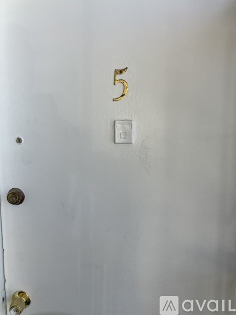 A white door with a gold number 5 and a light switch.