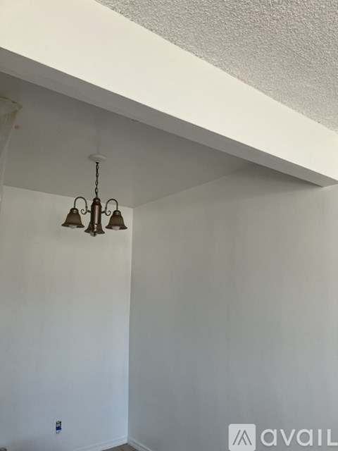 A chandelier hangs from the ceiling in a room with white walls.