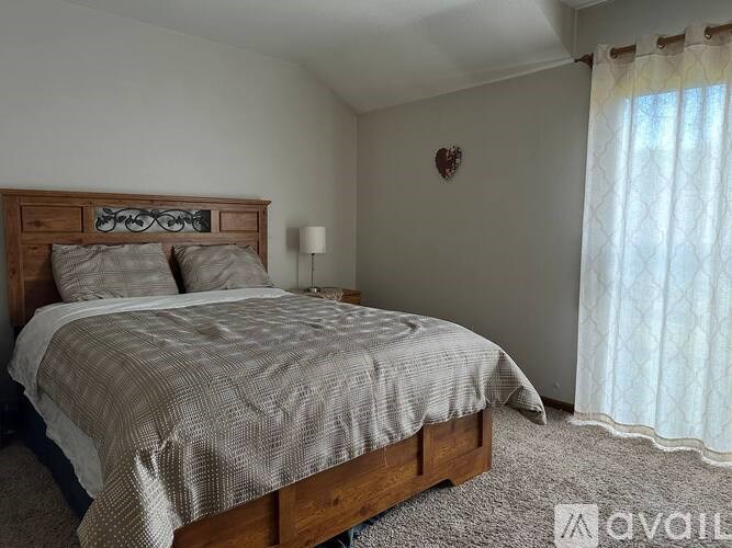 A bedroom with a bed, nightstand, and window.