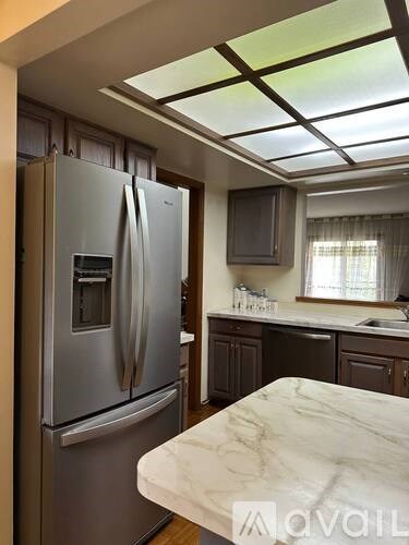 A kitchen with a marble top counter and a stainless steel refrigerator.