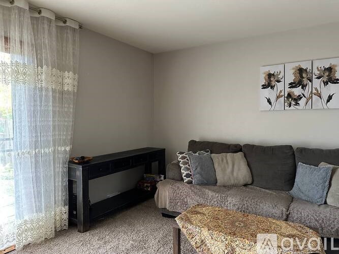 A living room with a grey couch and a piano.