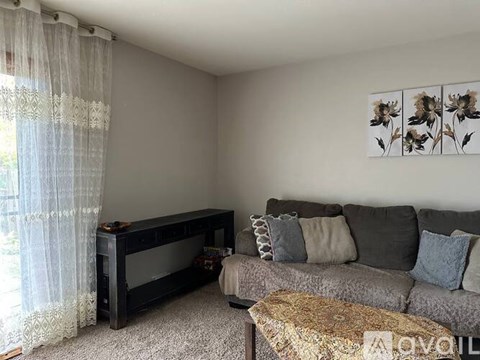 A living room with a grey couch and a piano.
