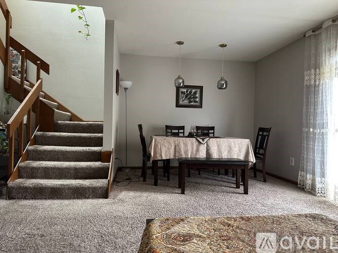 A living room with a staircase, a dining table, and chairs.