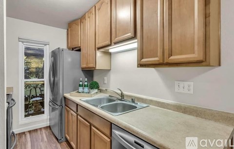 A kitchen with wooden cabinets and a stainless steel refrigerator.