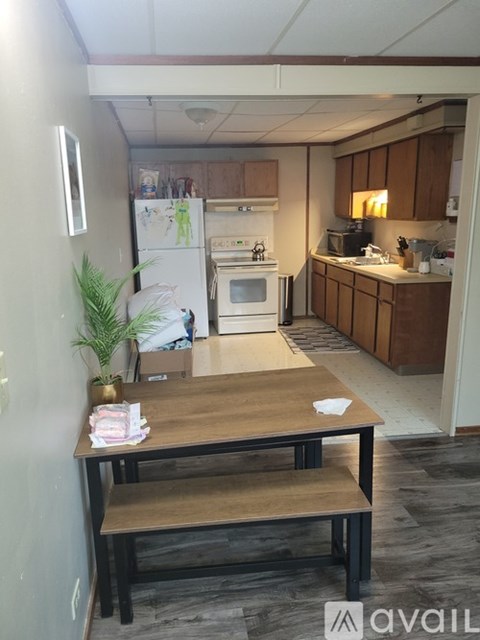 A kitchen with a table and chairs in the foreground and a refrigerator, oven, and microwave in the background.