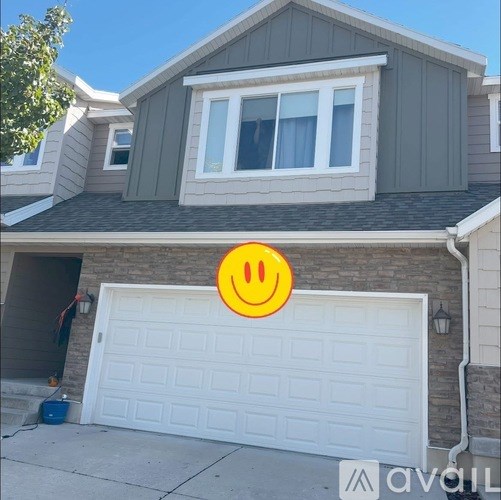 A house with a white garage door and a window with white curtains.