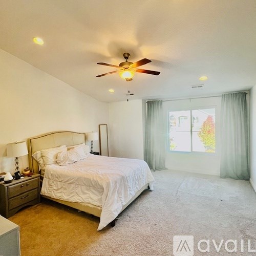 A bedroom with a large bed and a ceiling fan.