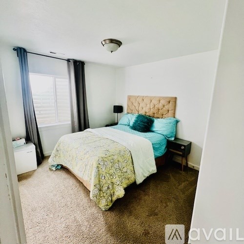 A bedroom with a bed, nightstand, and window with curtains.