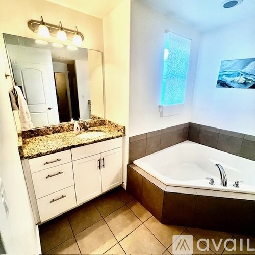 A bathroom with granite countertops and white cabinets.