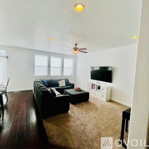 A living room with a couch, a television, and a ceiling fan.