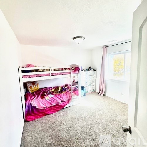 A bedroom with a bunk bed and a window with curtains.