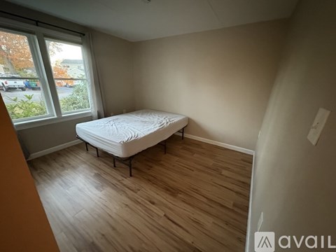 A bedroom with a bed and wooden flooring.