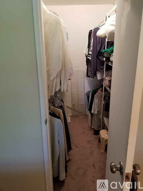 A hallway with a carpeted floor and a white door on the left.