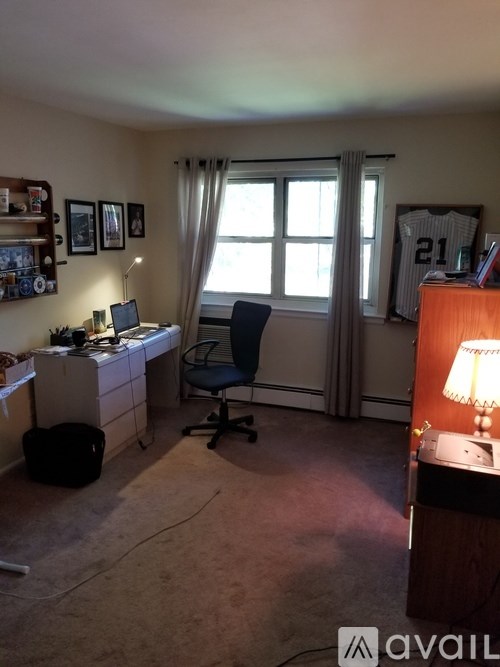 A room with a desk, chair, and a lamp.