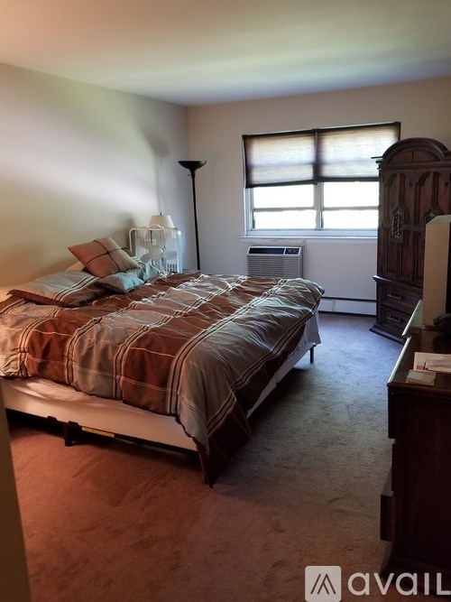 A bedroom with a bed, nightstand, and window.