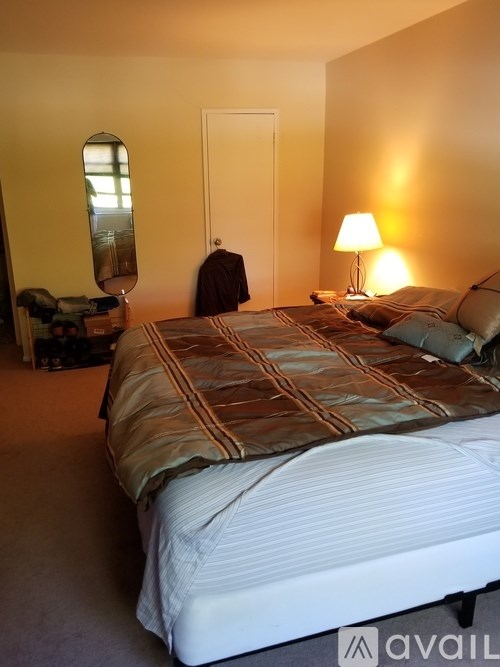 A bedroom with a bed, a chair, and a lamp.