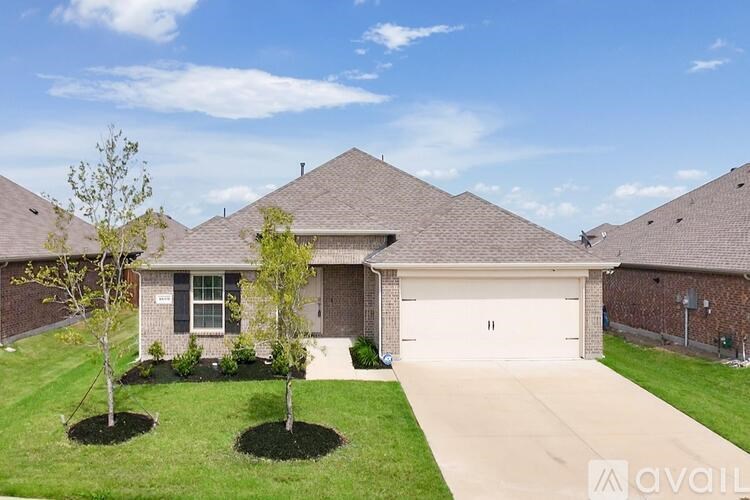 A house with a driveway and two trees in front.