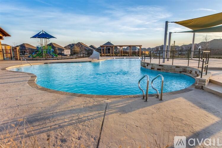 A large outdoor swimming pool with a blue umbrella and slide in the background.