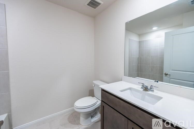 A bathroom with a toilet, sink, and mirror.