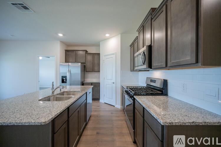 A kitchen with granite countertops and dark wood cabinets.