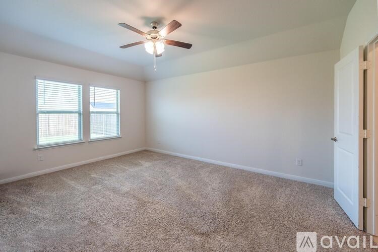 A room with a ceiling fan and carpeted floor.