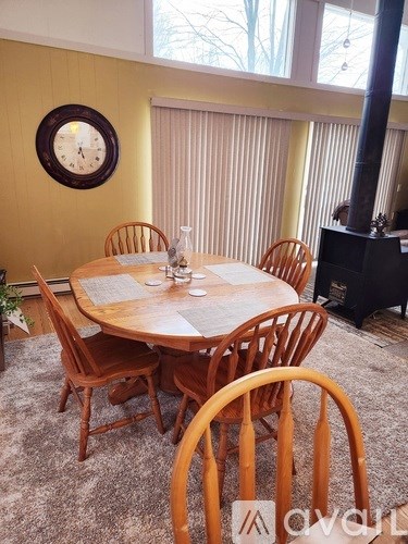 A wooden dining table with chairs and a clock on the wall.
