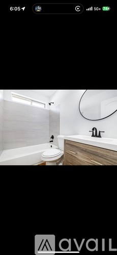 A bathroom with a white tub and a wooden vanity.